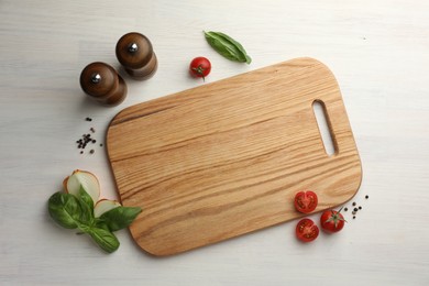 Photo of Cutting board, basil, onion, pepper and tomatoes on white wooden table, flat lay. Space for text