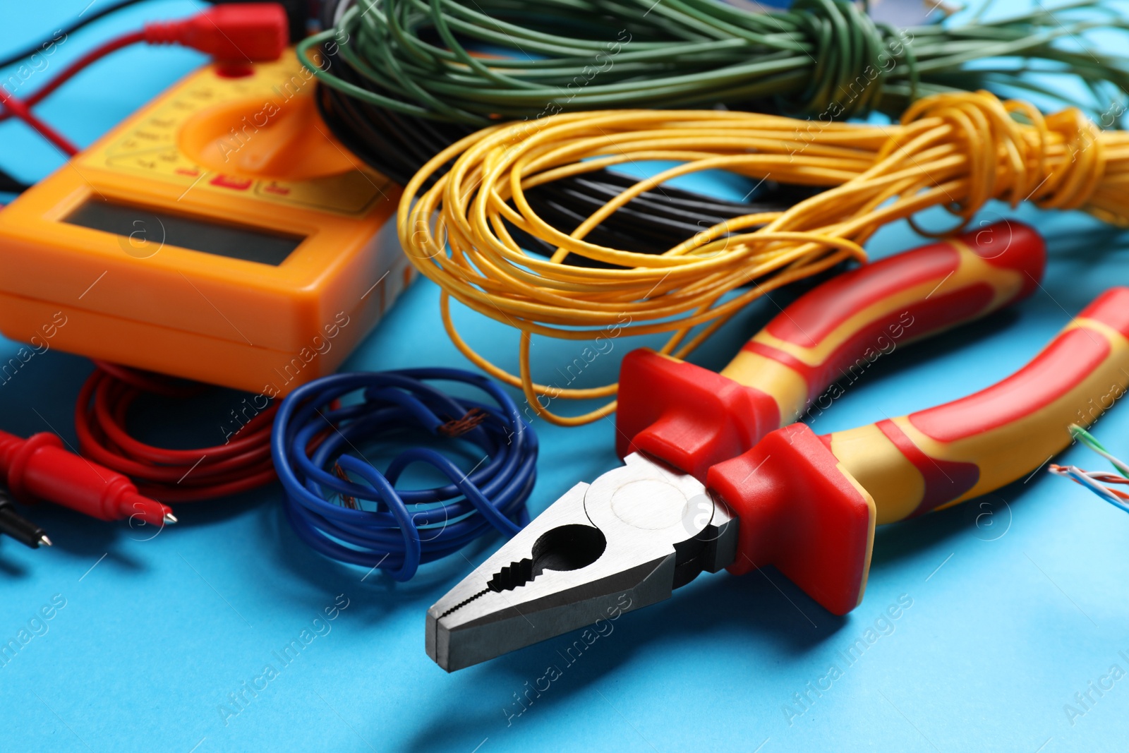 Photo of Set of electrician's tools and accessories on light blue background