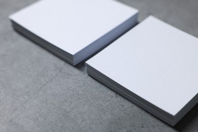 Blank paper sheets on grey textured table, closeup. Mockup for design