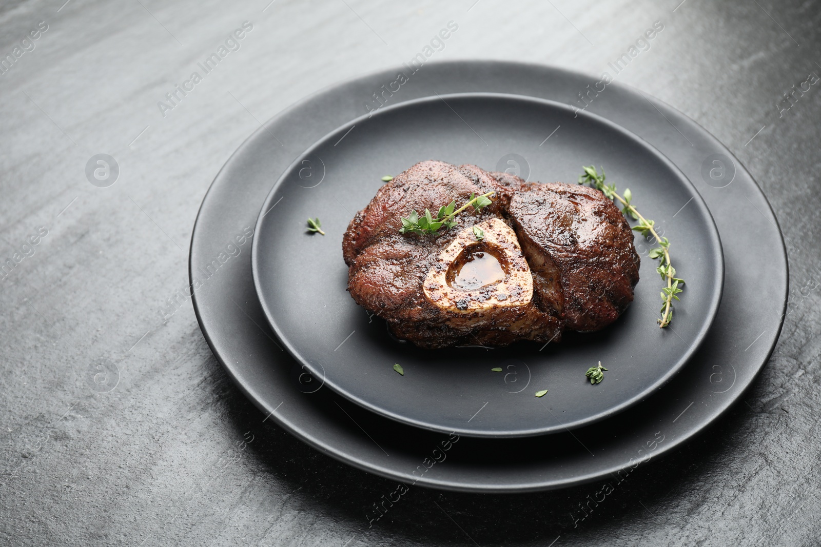 Photo of Delicious roasted beef meat with thyme on black table