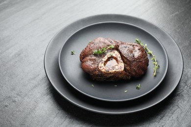 Delicious roasted beef meat with thyme on black table