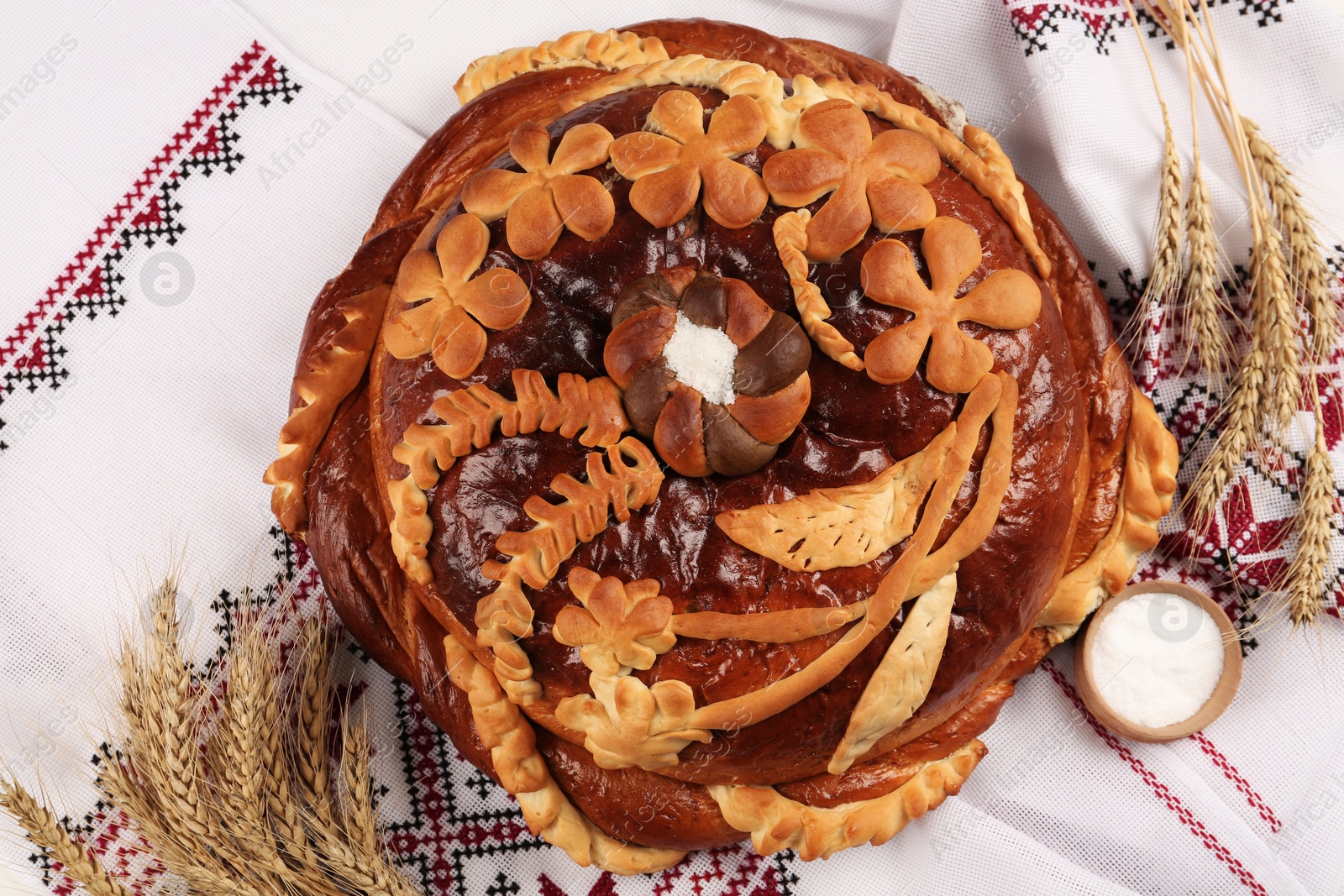 Photo of Korovai with wheat spikes on rushnyk, flat lay. Ukrainian bread and salt welcoming tradition