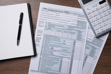 Photo of Payroll. Tax return forms, calculator, notebook and pen on wooden table, flat lay