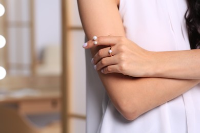 Photo of Young woman wearing elegant rings with pearls indoors, closeup. Space for text