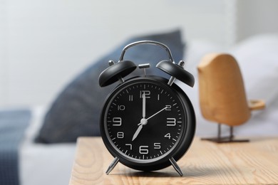 Photo of Black alarm clock on wooden nightstand in bedroom