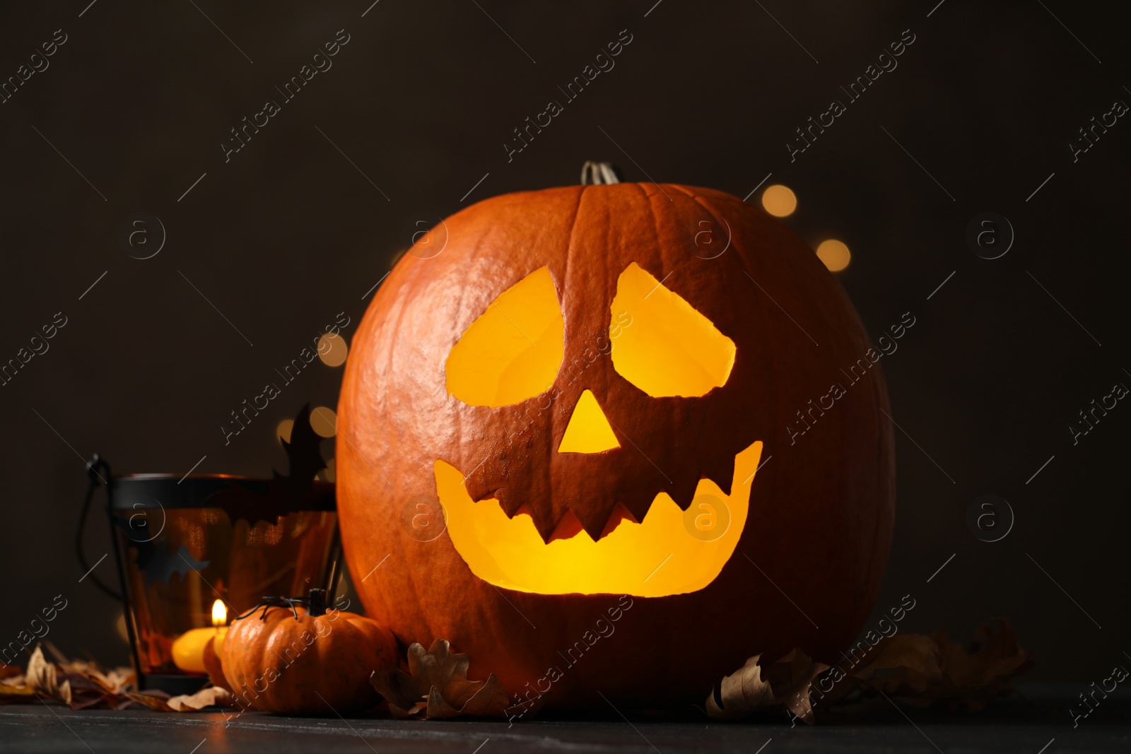 Photo of Pumpkin jack o'lantern and Halloween decor on table against dark background