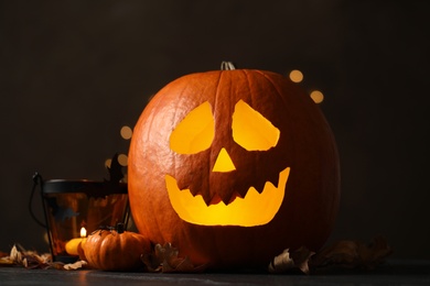 Photo of Pumpkin jack o'lantern and Halloween decor on table against dark background