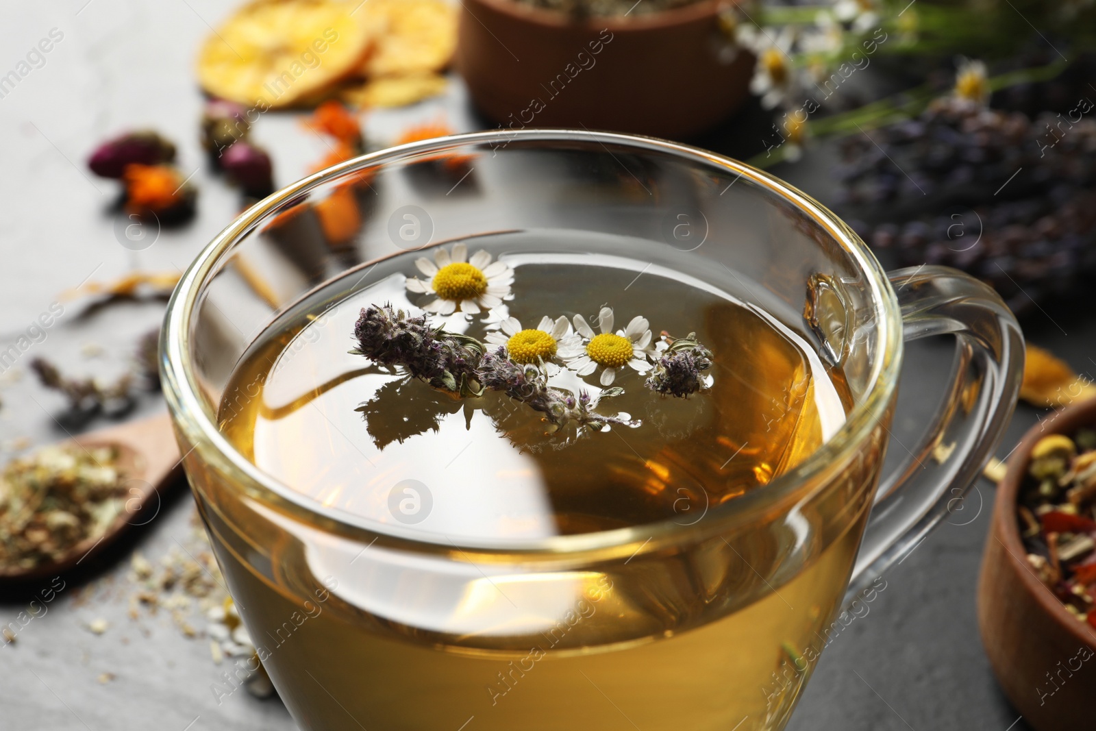 Photo of Glass cup of aromatic herbal tea on table, closeup