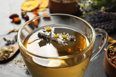 Photo of Glass cup of aromatic herbal tea on table, closeup