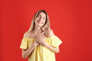 Portrait of woman holding hands near heart on color background. Space for text