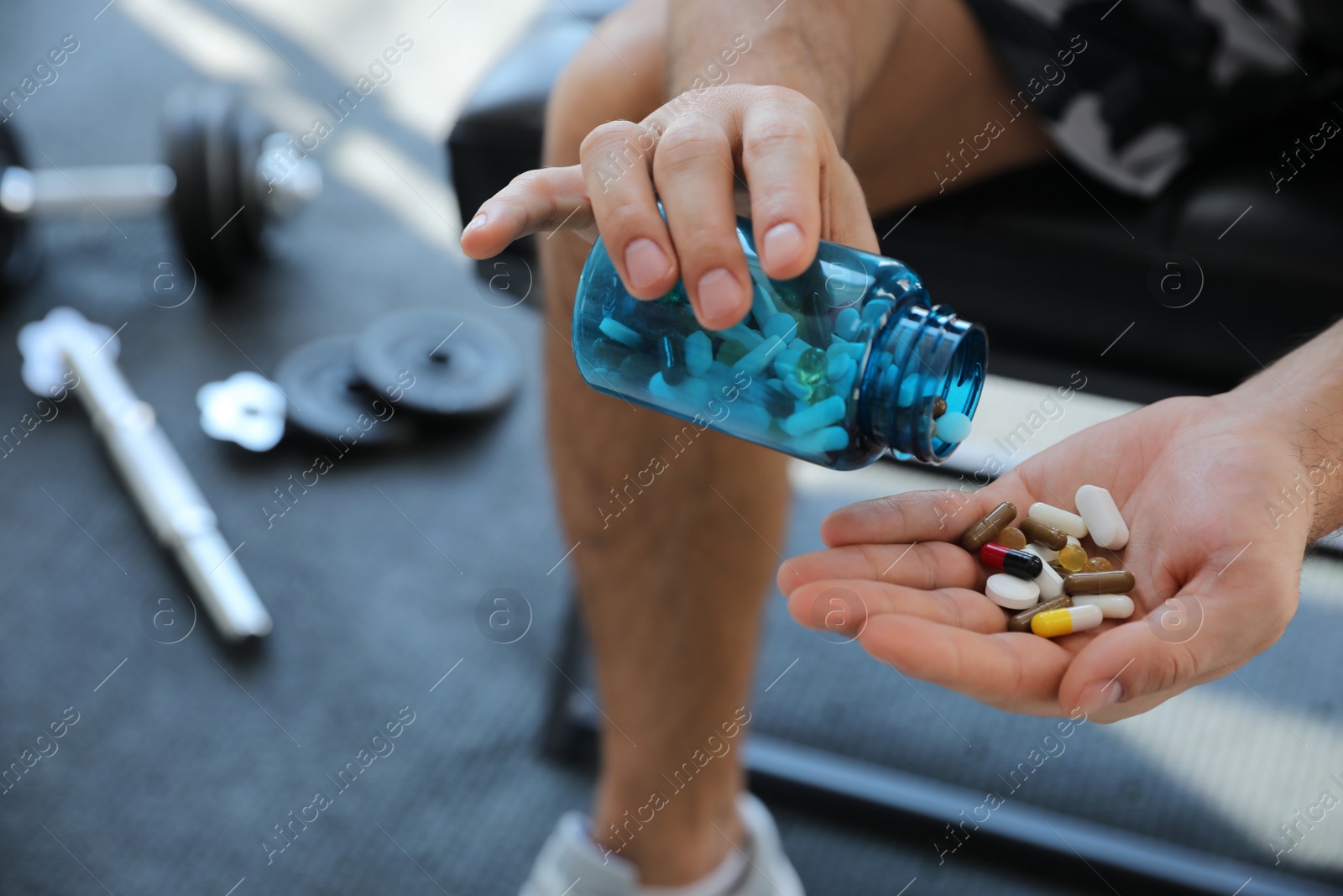 Photo of Sportsman with bottle of pills in gym, closeup. Doping concept