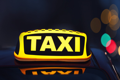 Taxi car with yellow roof sign on city street in evening, closeup