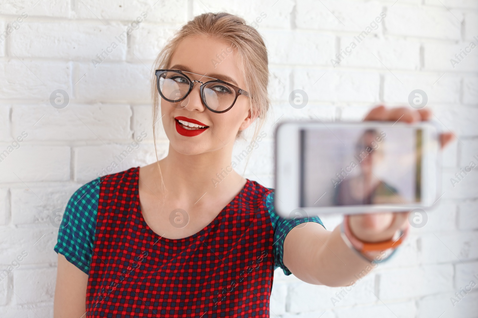 Photo of Attractive young woman taking selfie near brick wall