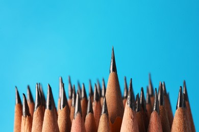 Photo of Many sharp graphite pencils on light blue background, closeup. Space for text