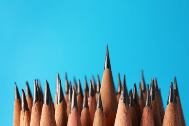 Many sharp graphite pencils on light blue background, closeup. Space for text