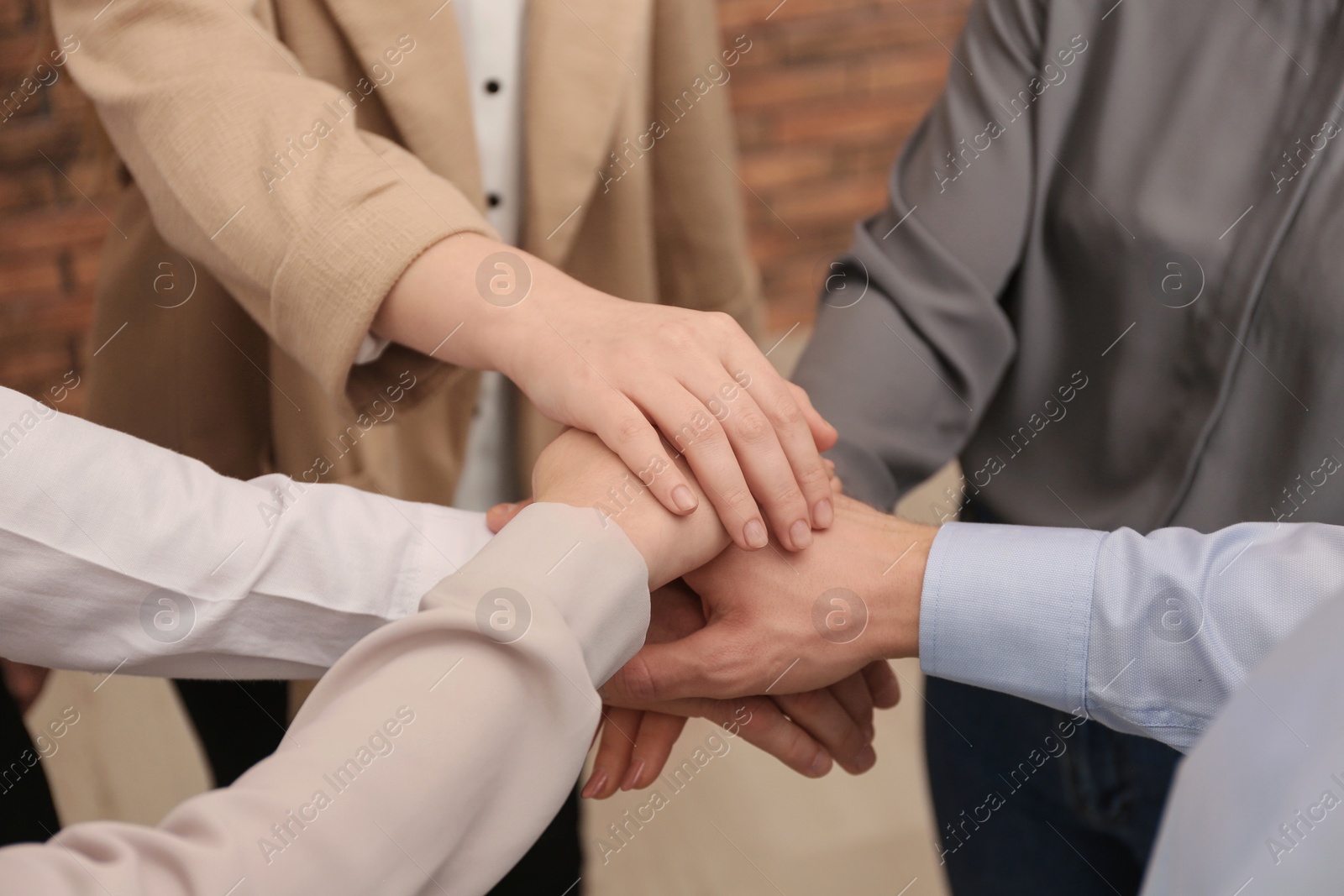 Photo of Group of people holding their hands together indoors, closeup