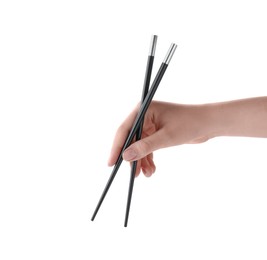 Photo of Woman holding pair of black chopsticks on white background, closeup