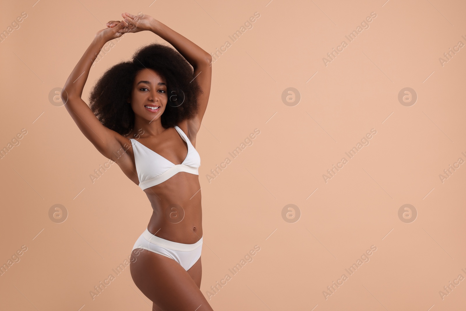 Photo of Beautiful woman in stylish bikini on beige background, space for text