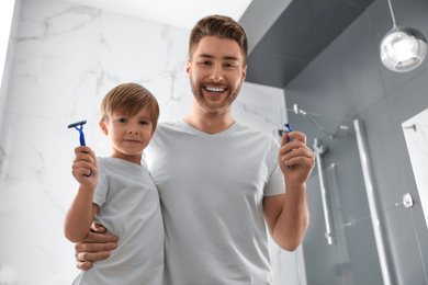 Photo of Dad and son with razors in bathroom, low angle view