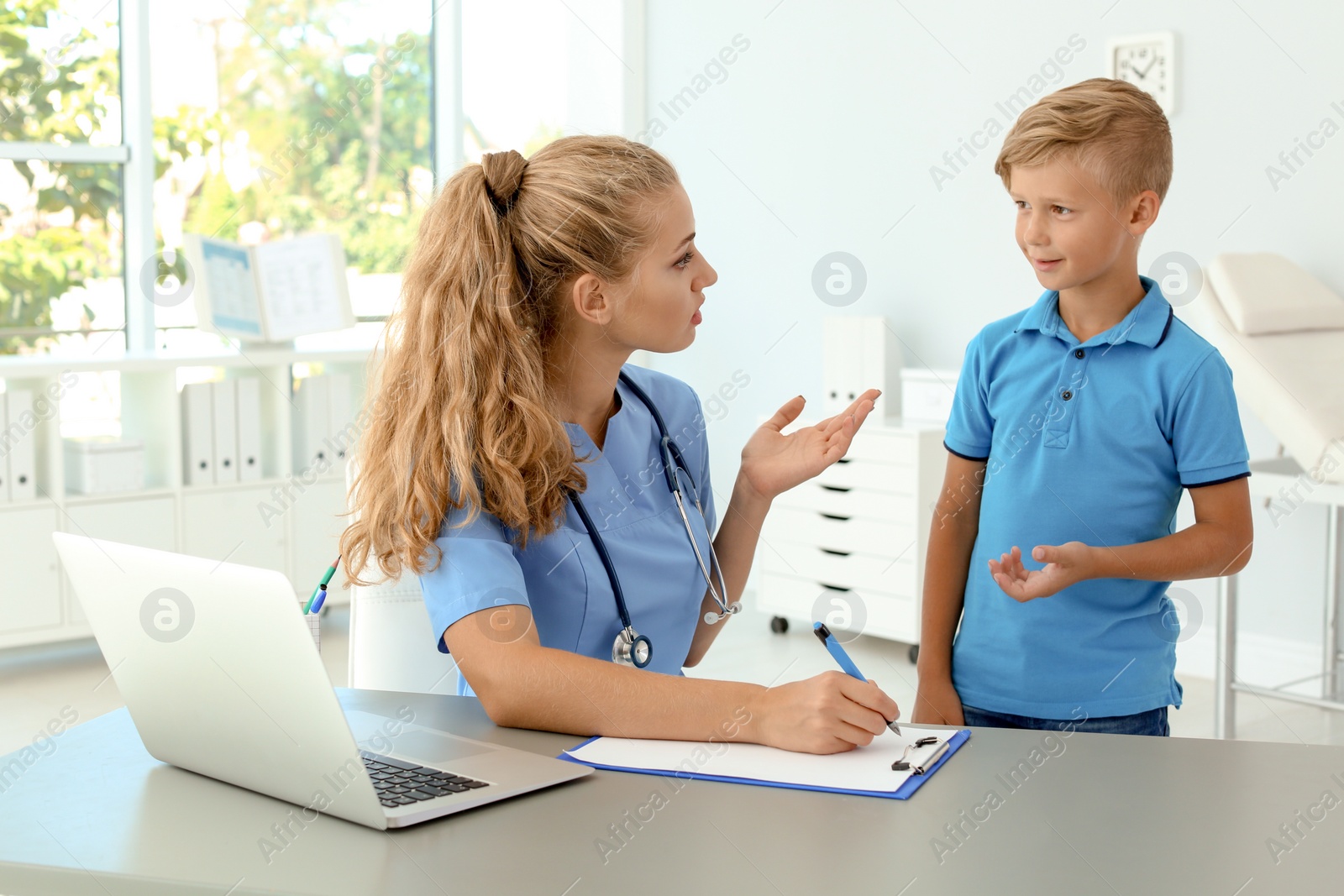 Photo of Female medical assistant consulting child in clinic