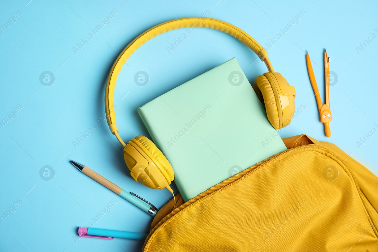 Photo of Flat lay composition with book and headphones on light blue background