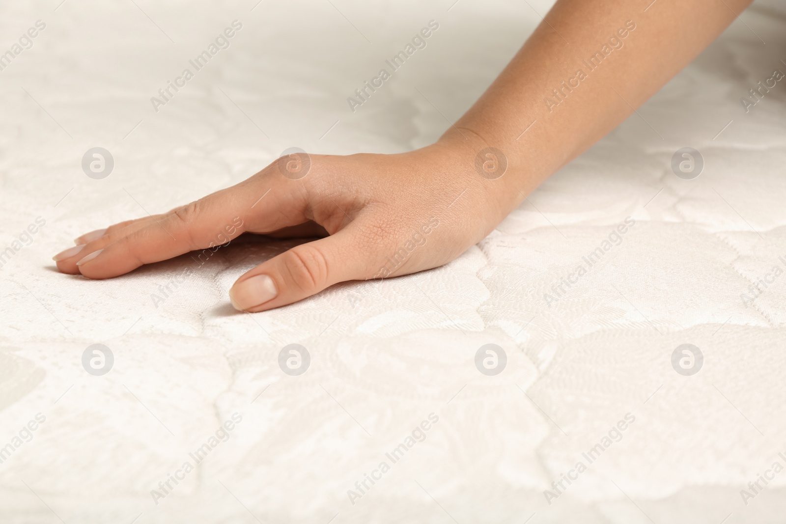 Photo of Woman touching soft comfortable mattress, closeup of hand