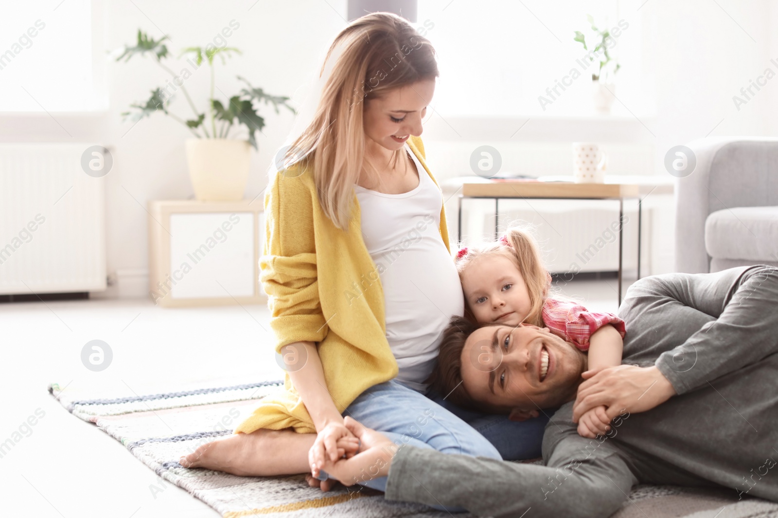 Photo of Young pregnant woman with her family at home