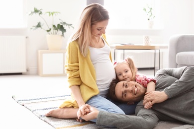 Young pregnant woman with her family at home