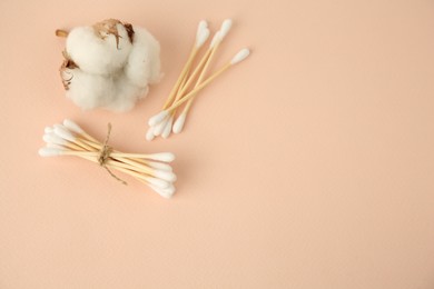 Photo of Cotton buds and flower on beige background, flat lay. Space for text