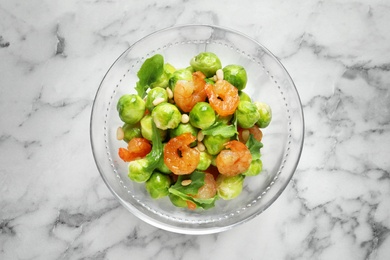 Photo of Bowl of delicious salad with Brussels sprouts and shrimps on marble table, top view