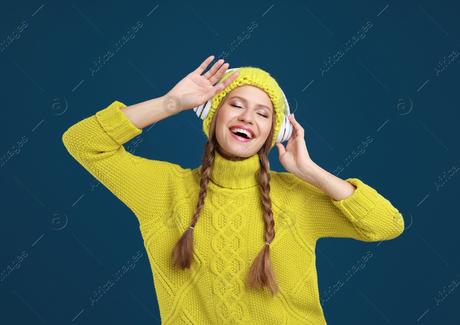 Photo of Young woman listening to music with headphones on dark blue background