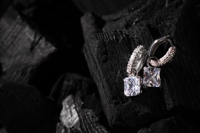 Photo of Luxury jewelry. Stylish presentation of elegant earrings on coal, closeup with space for text