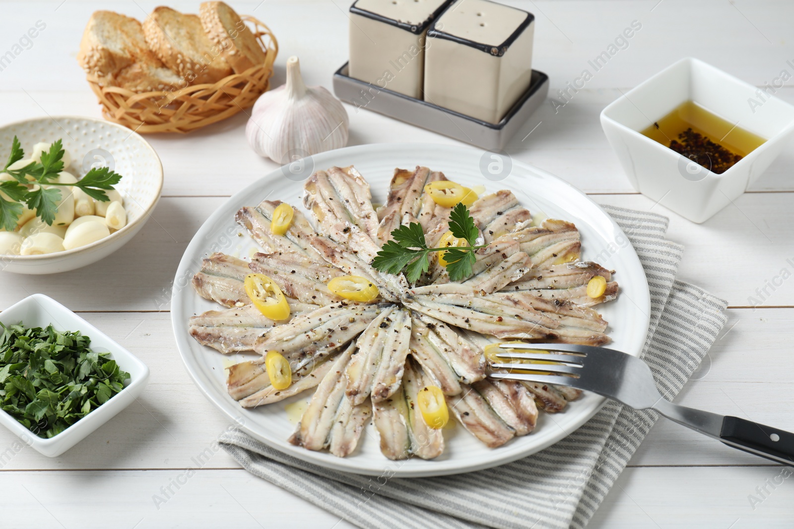 Photo of Tasty pickled anchovies served on white wooden table