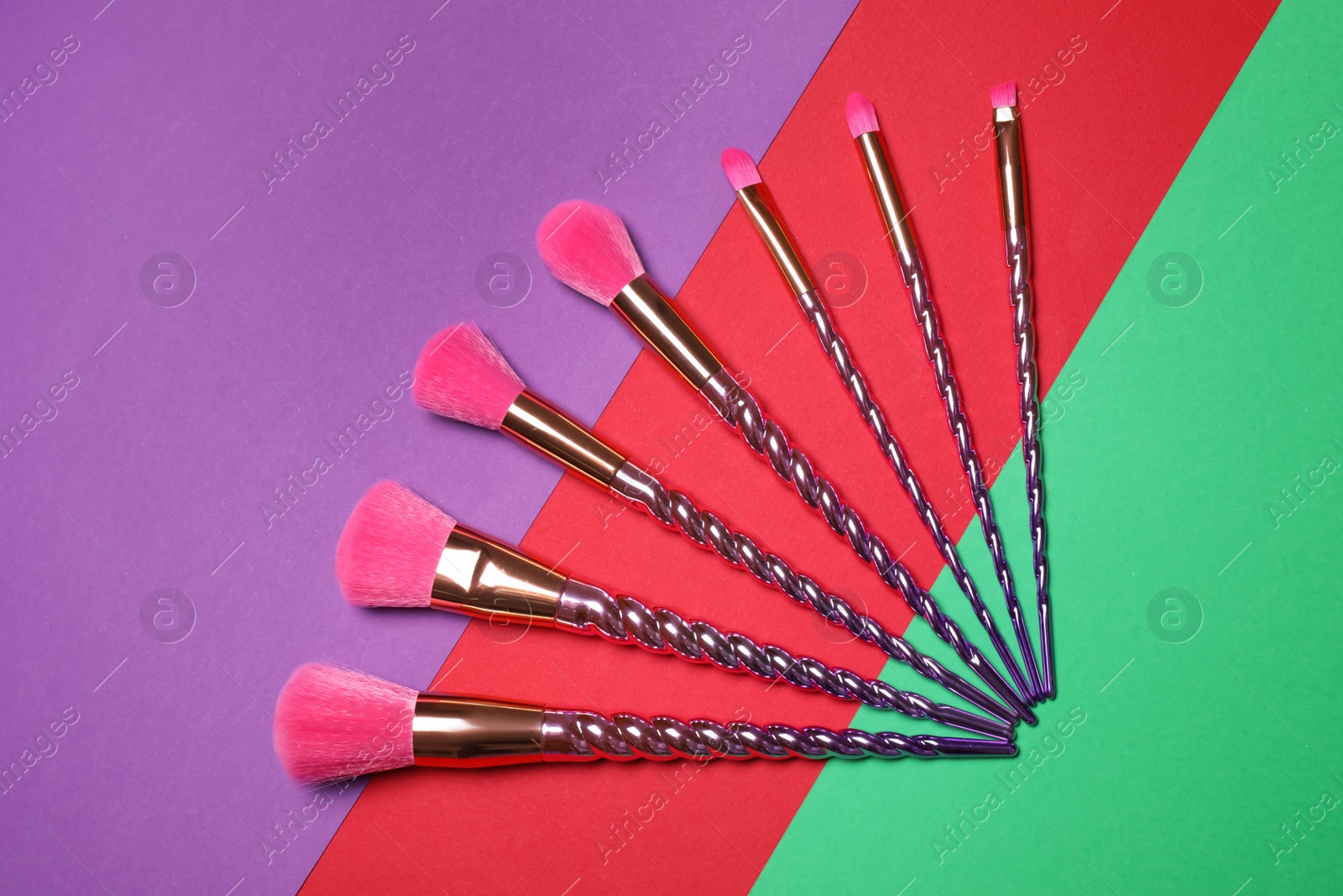 Photo of Set of makeup brushes on color background, flat lay