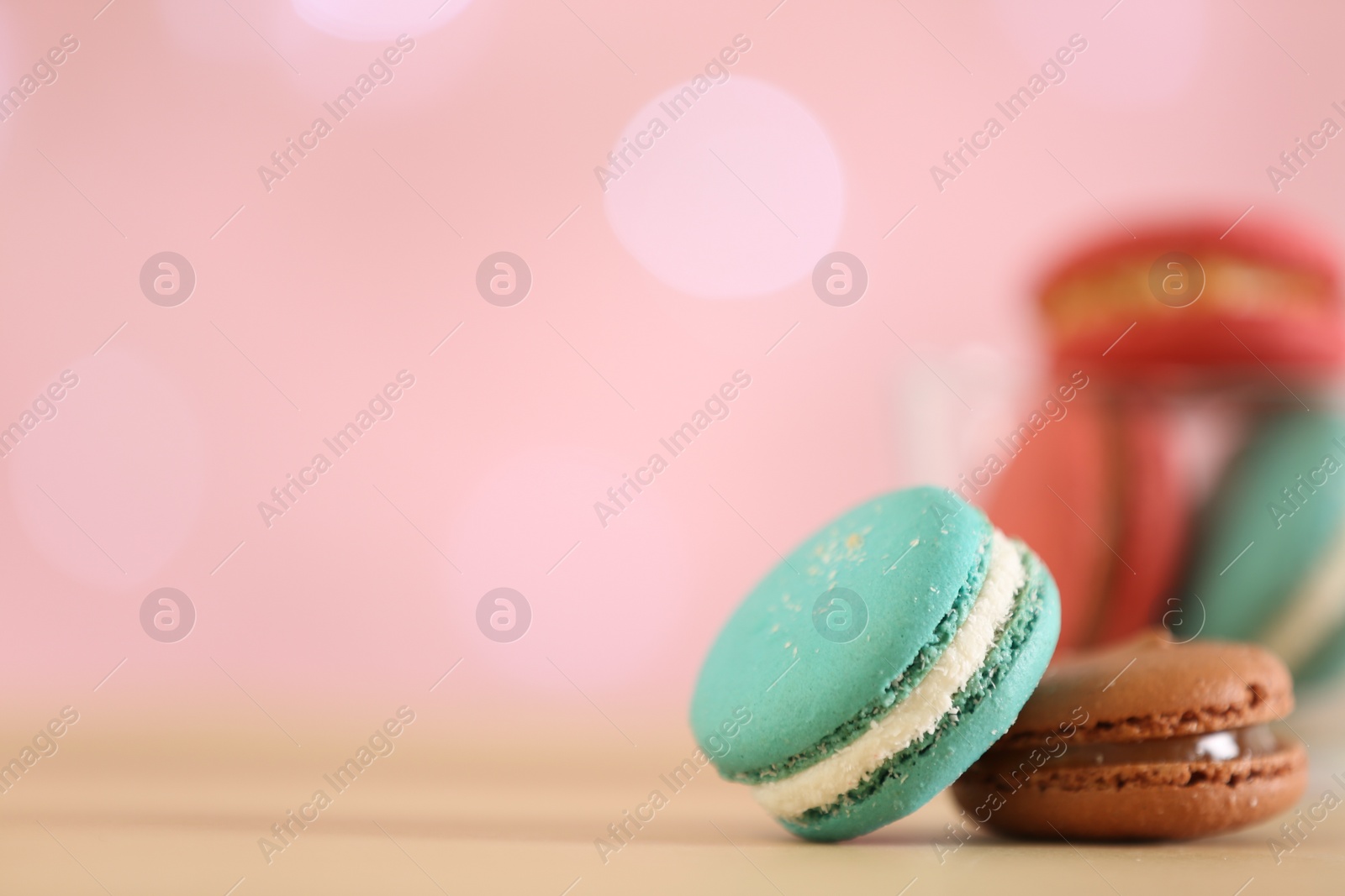 Photo of Delicious macarons on table against blurred background, closeup. Space for text