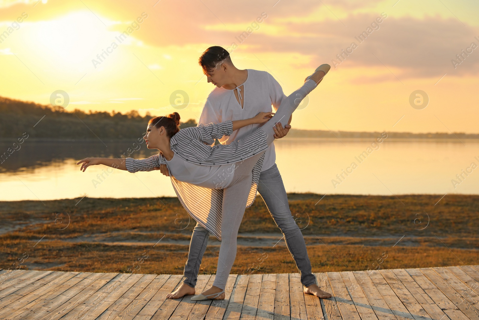 Photo of Beautiful young couple practicing dance moves near river at sunset