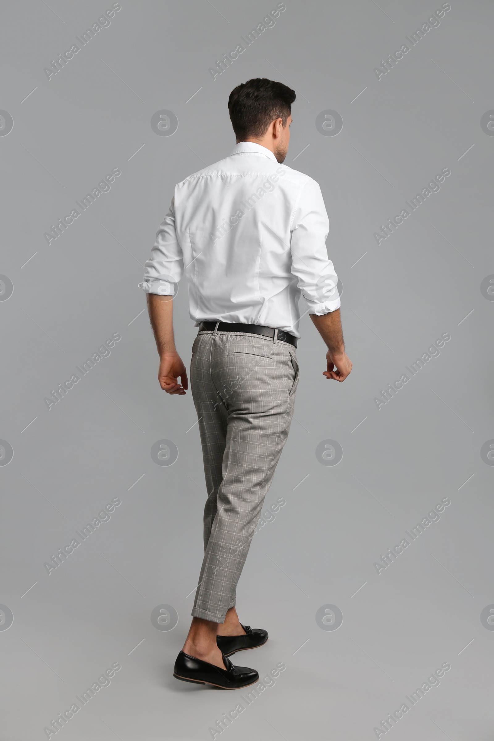 Photo of Businessman in formal clothes on grey background, back view