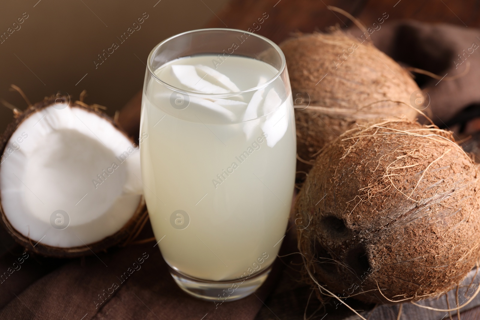 Photo of Glass of coconut water and nuts on wooden table