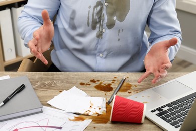 Photo of Man with spilled coffee over his workplace and shirt, closeup
