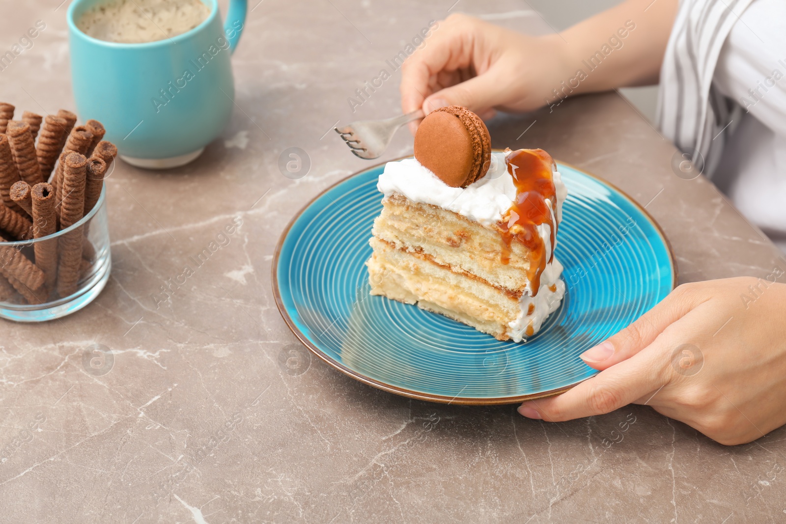 Photo of Woman eating delicious homemade cake with caramel sauce at table