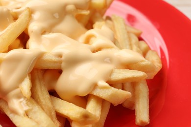 Delicious french fries with cheese sauce on plate, closeup