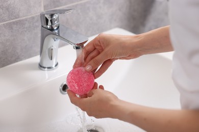 Photo of Young woman washing face sponge in bathroom, closeup