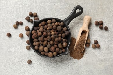 Photo of Ground allspice pepper, grains and scoop on grey table, flat lay