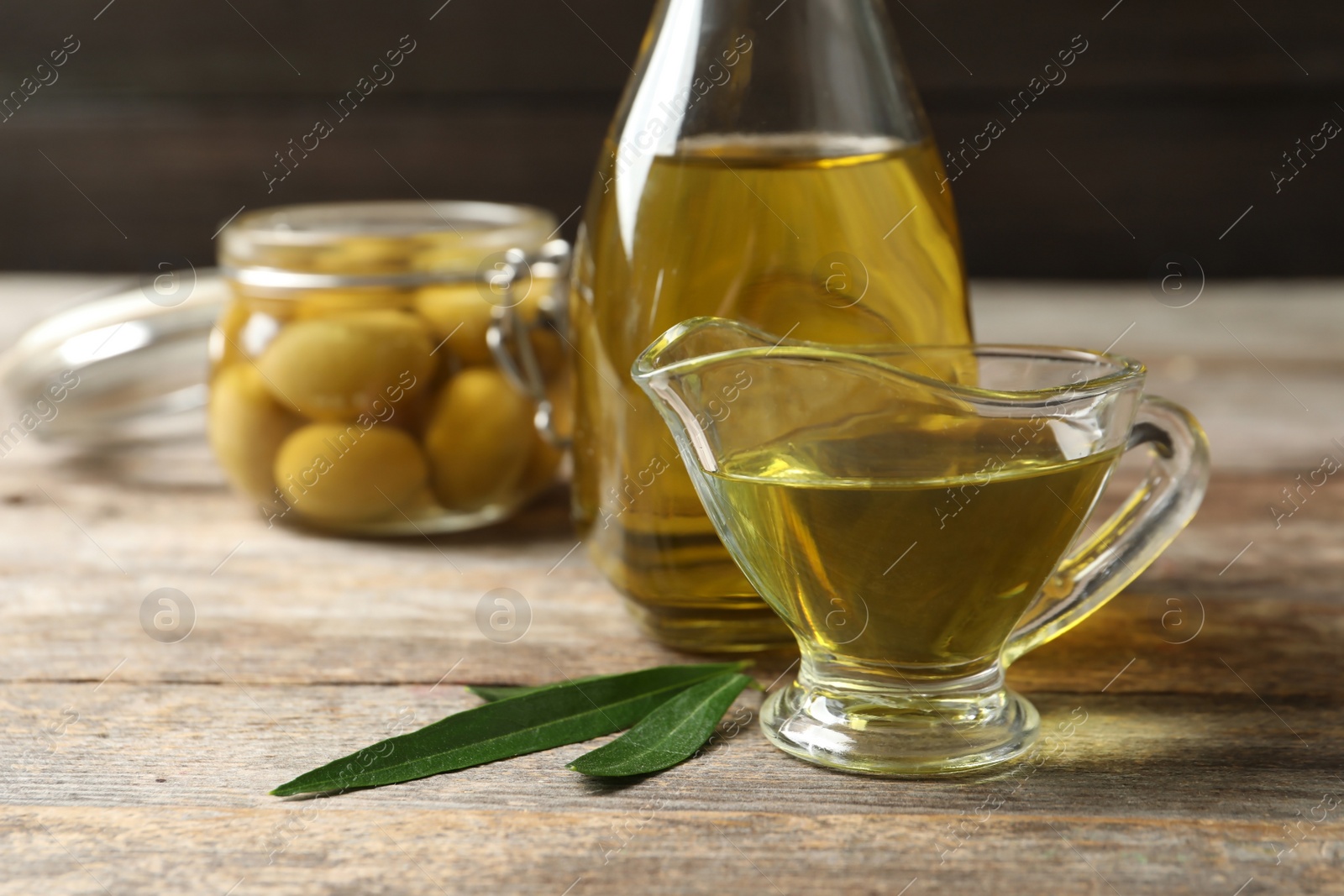 Photo of Gravy boat with fresh olive oil on wooden table, closeup