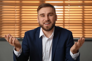 Photo of Young man in suit holding online webinar indoors, view from webcam