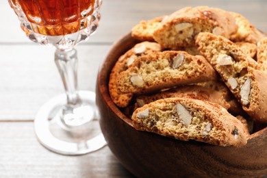 Traditional Italian almond biscuits (Cantucci) and glass of liqueur on wooden table, closeup. Space for text