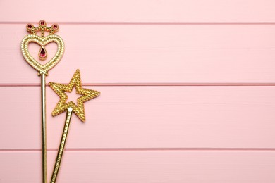 Photo of Different golden magic wands on pink wooden table, flat lay. Space for text