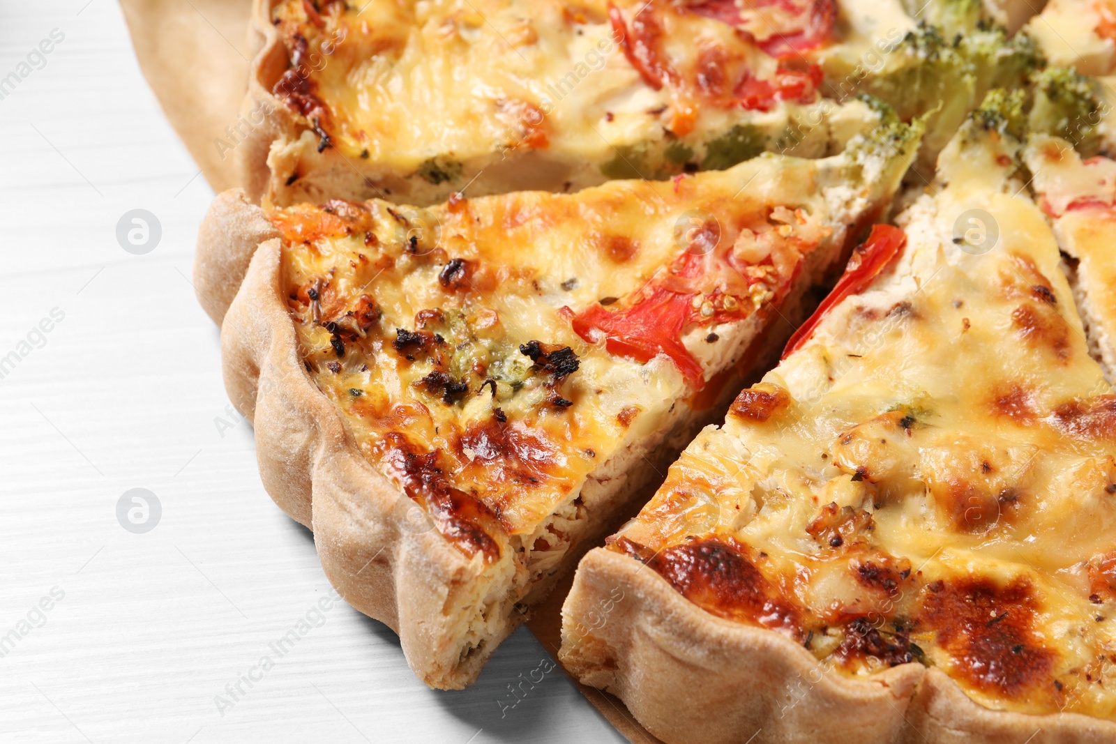 Photo of Tasty quiche with tomatoes and cheese on white wooden table, closeup