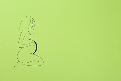 Photo of Pregnant woman figure drawn on light green background, top view with space for text. Surrogacy concept