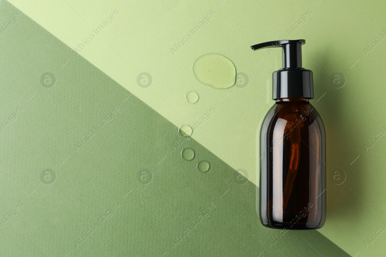 Photo of Bottle and drops of hydrophilic oil on color background, flat lay. Space for text